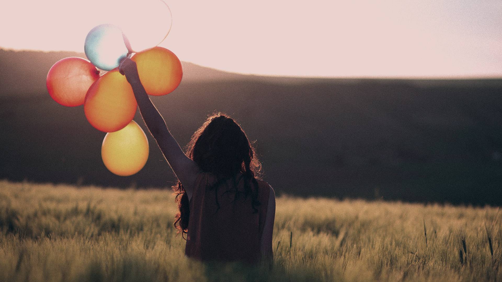 Junge Frau hält bunte Luftballons in die Sonne - Folge MAXENERGY auch in den sozialen Netzwerken und erfahre interessante Facts zu Strom und Gas