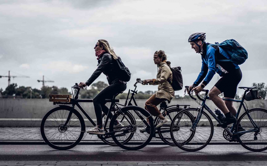 Drei Personen auf dem Weg zur Arbeit mit dem Fahrrad - wir zeigen Dir, wie Du umweltfreundlich ins Büro kommst.