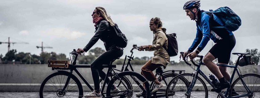 Drei Personen auf dem Weg zur Arbeit mit dem Fahrrad - wir zeigen Dir, wie Du umweltfreundlich ins Büro kommst.