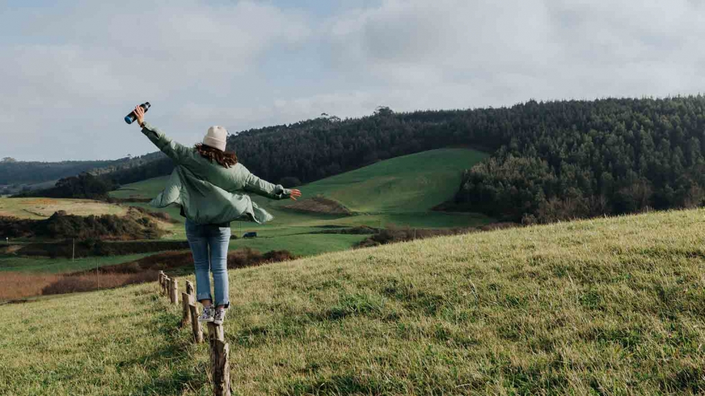 Frau balanciert auf Wiese. Warum leben wir nicht so nachhaltig wie wir wollen?
